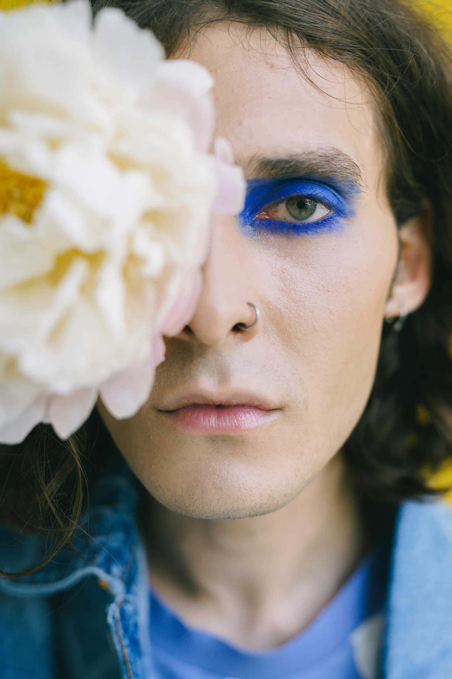 a person with a blue make - up is holding a flower