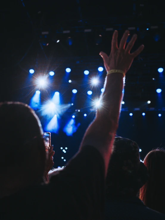 a large crowd is at a concert and someone is holding their hand up