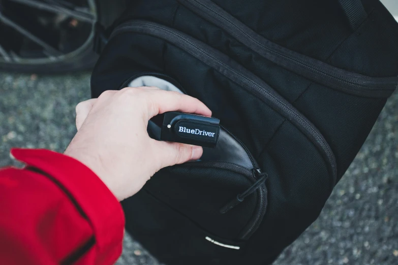 hand with remote control on shoulder of backpack