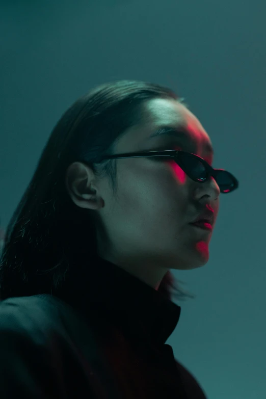 woman wearing black sunglasses with a red light shining down on her face