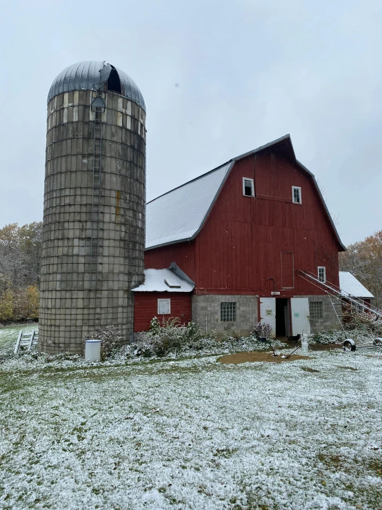 an old brick barn in front of snow covered trees