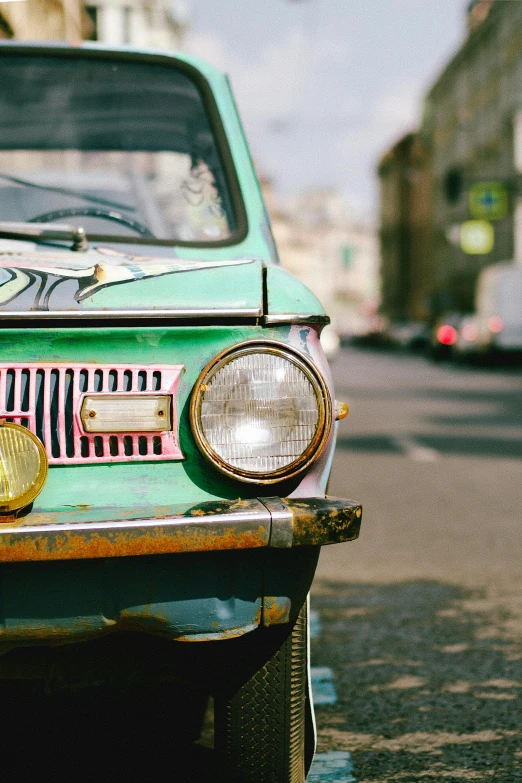 the front of an old green car with graffiti on it