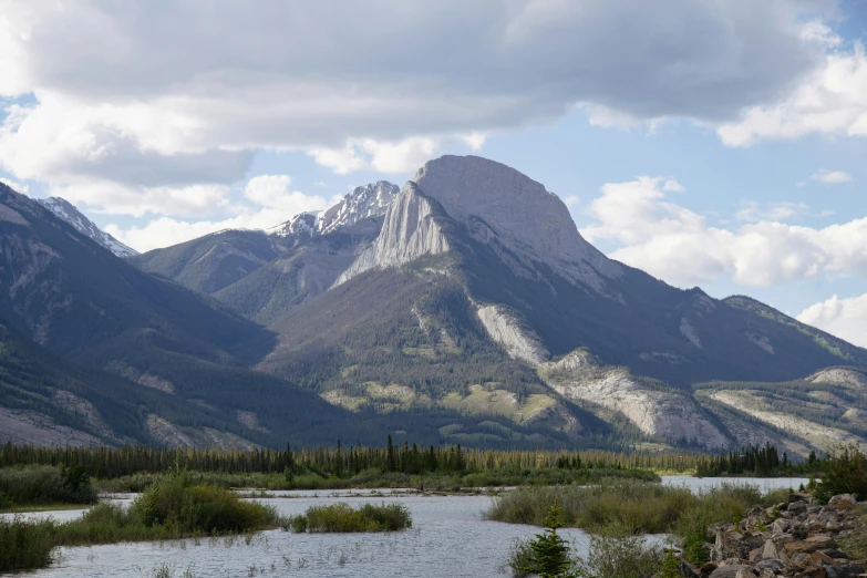 a small river near a mountain range under cloudy skies