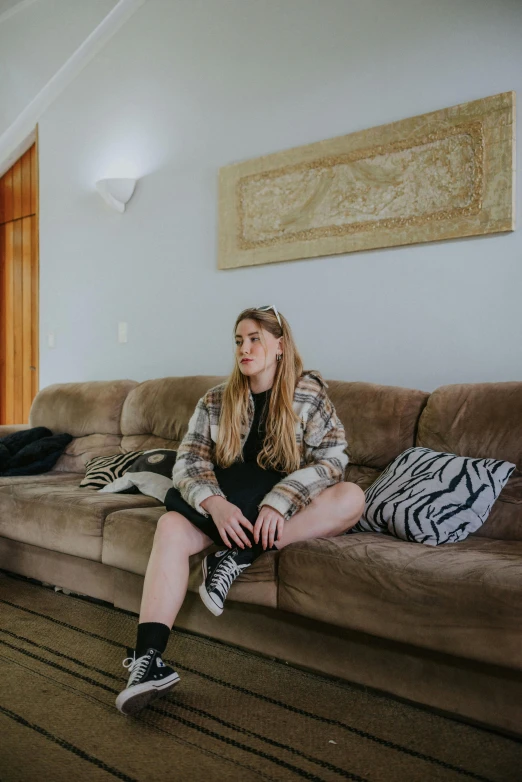 a girl in plaid shirt sitting on a couch in a room