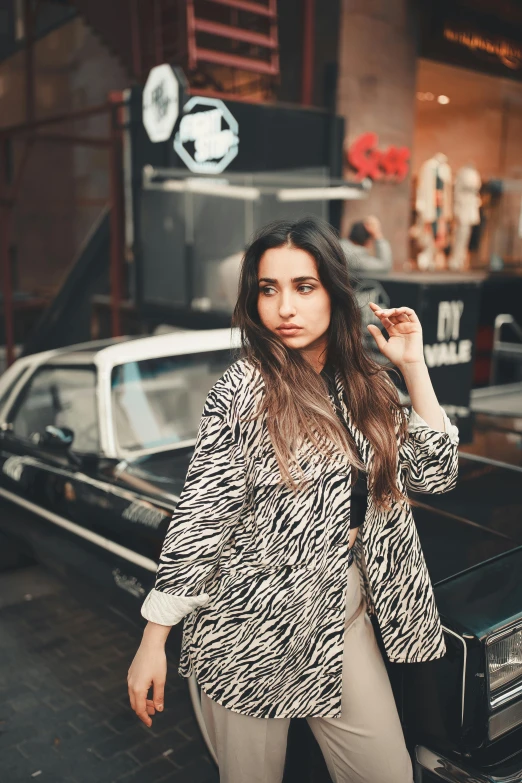 young woman standing next to vintage car holding hat