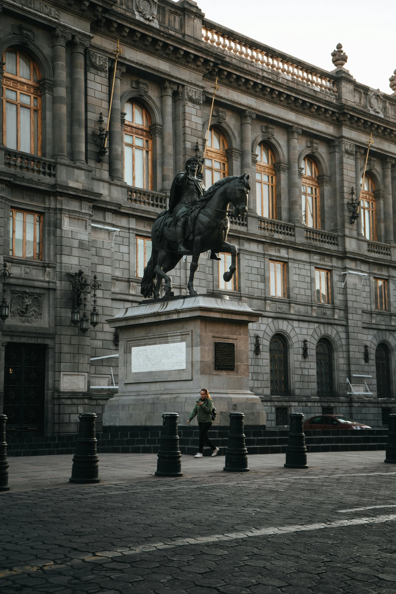 a person is sitting on a horse statue in front of a building