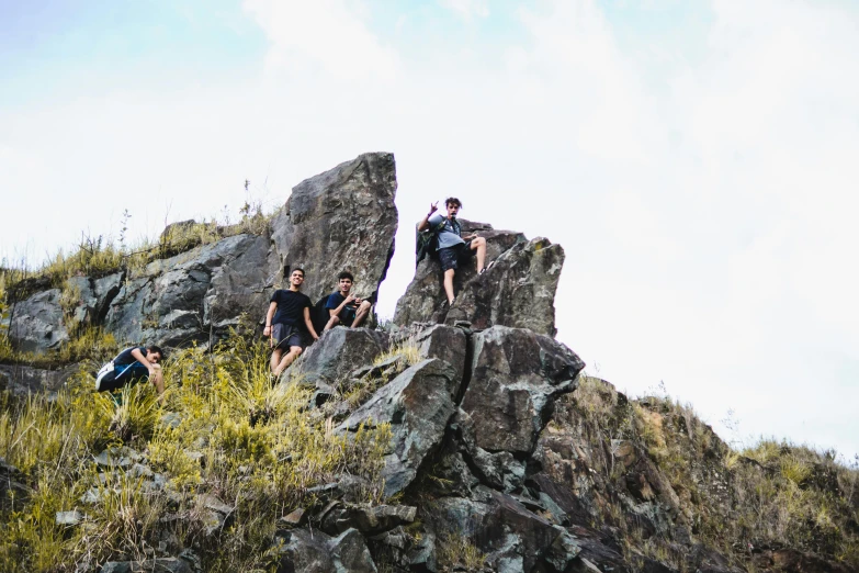 people stand on rocks while one person climbing