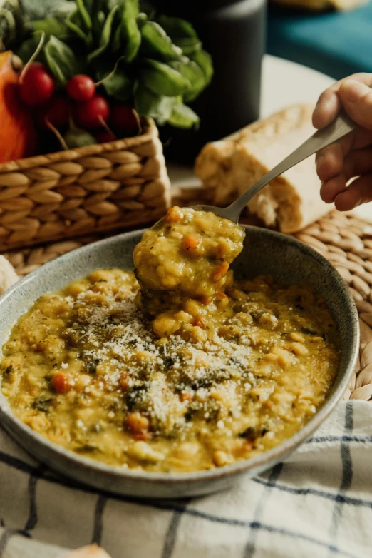 someone is holding a spoon to a bowl filled with a creamy soup