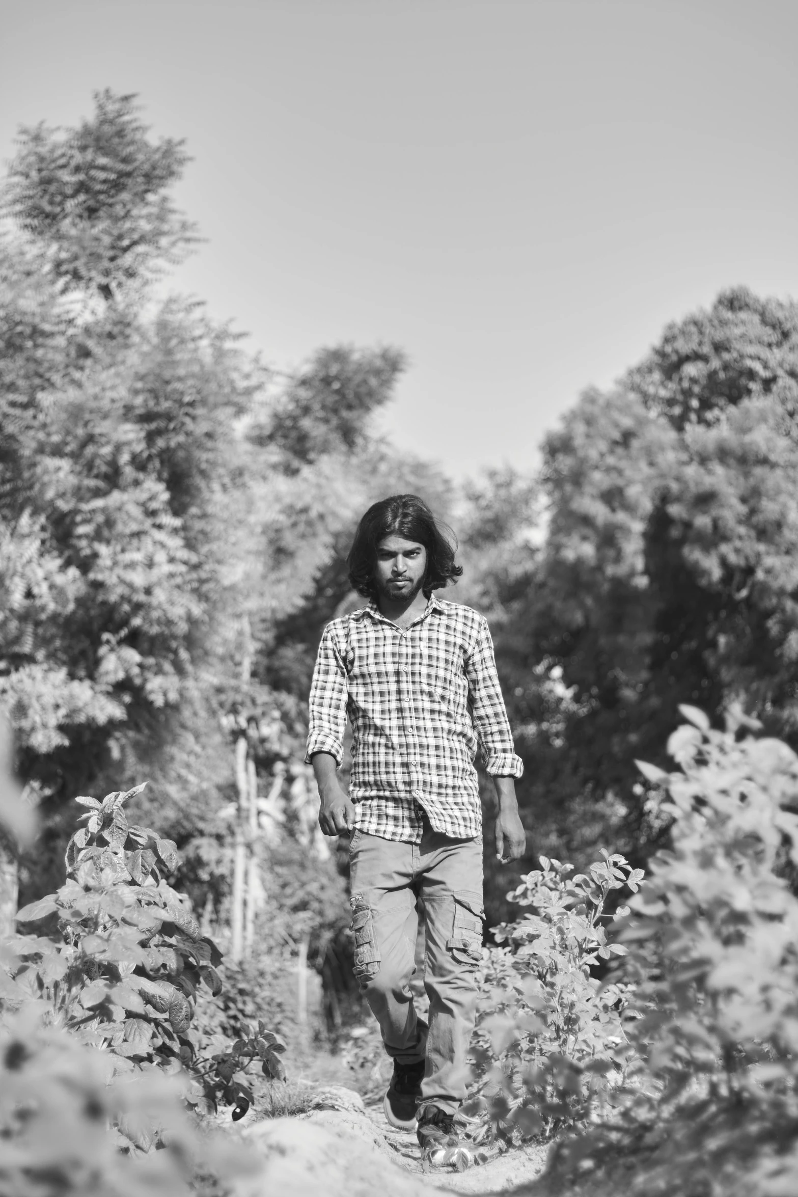 black and white po of young man walking through an area with trees