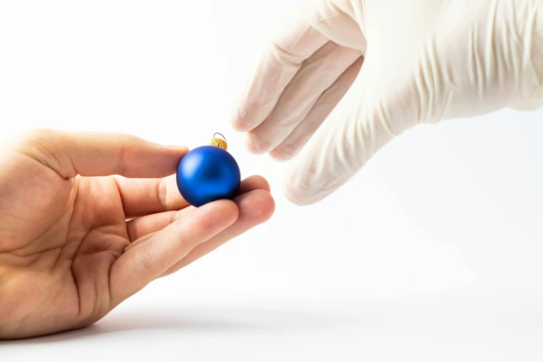 a gloved hand reaches for a blue ornament