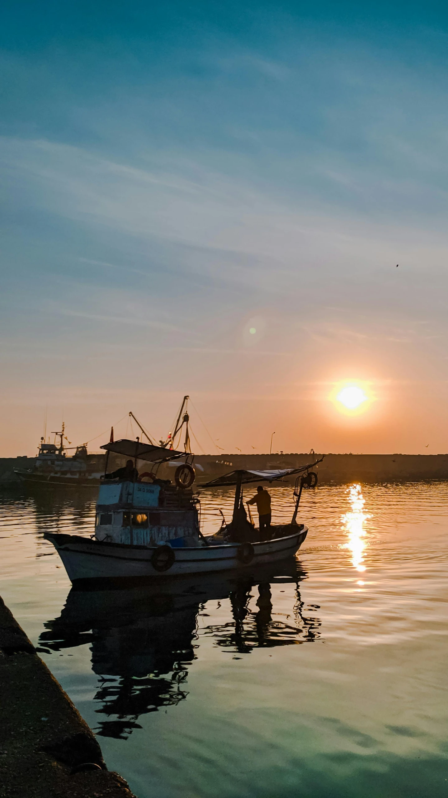 a boat on the water in front of a pier at sunset