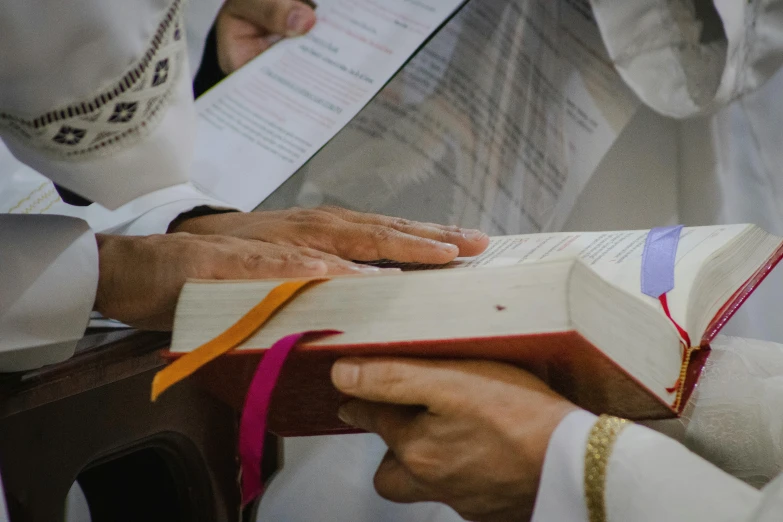 two priests reading paper notes in a religious book