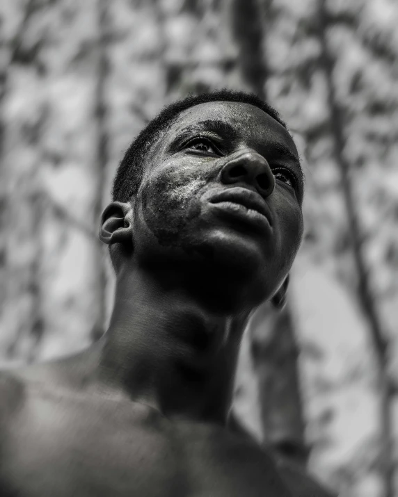 a black man stands in front of trees