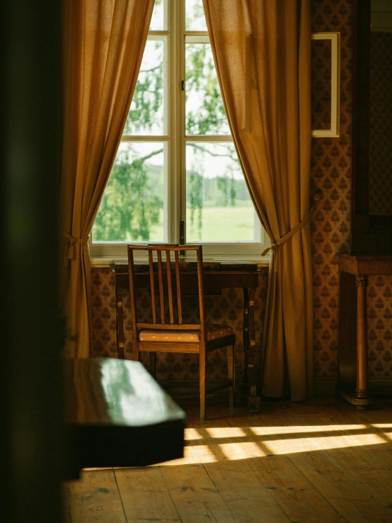 the room has three wooden chairs, two windows and a table in it