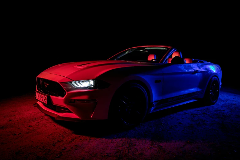 a red, white and blue ford mustang in the dark