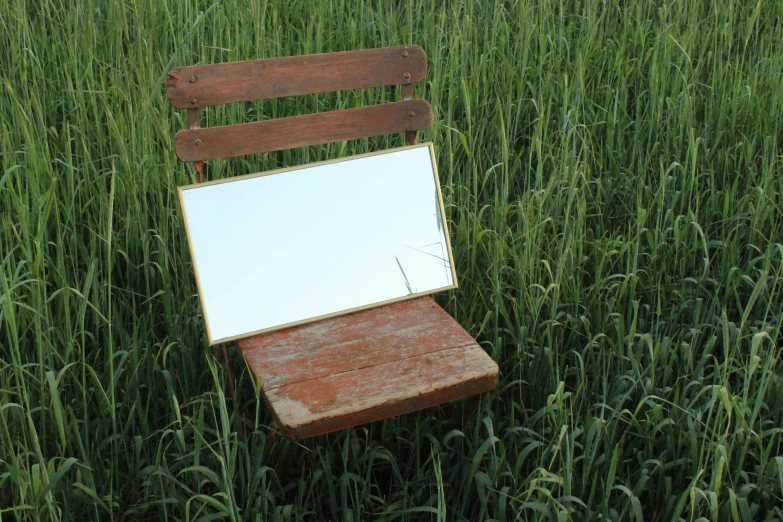 an old wooden chair is in the middle of tall grass