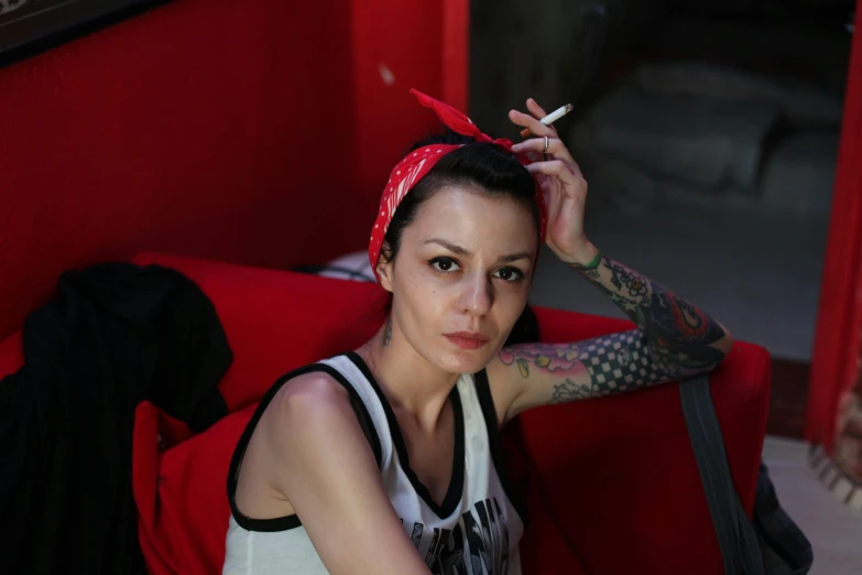 a woman smoking a cigarette sitting in a red chair