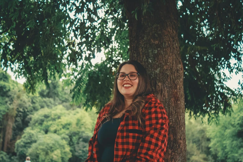 a girl posing under a tree next to a path