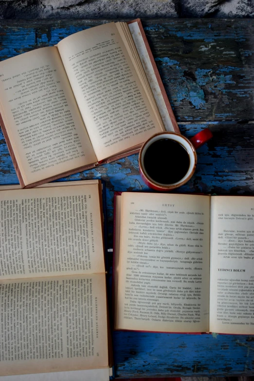 two open books sitting on top of a table next to a coffee cup