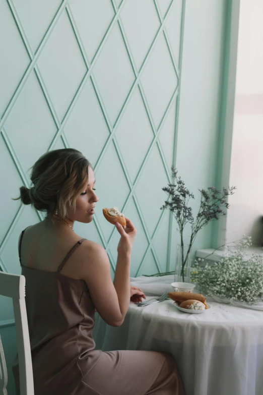 the woman is eating a pastry on the table