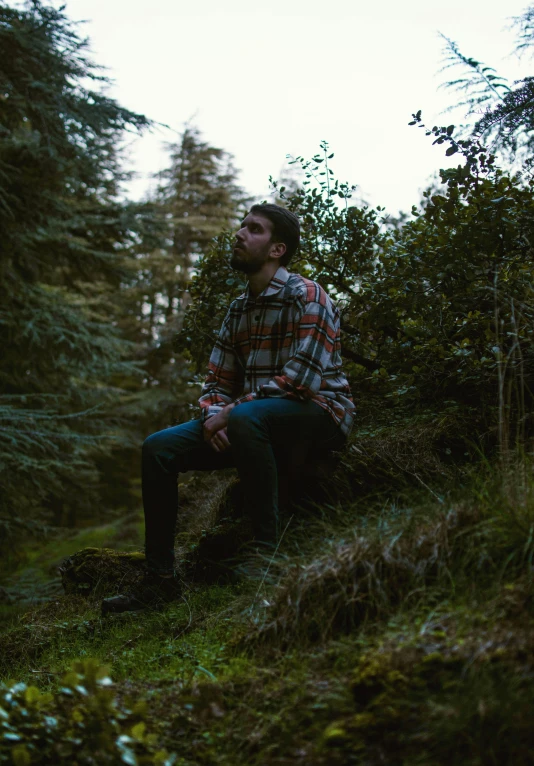 a man sitting on top of a log in the forest