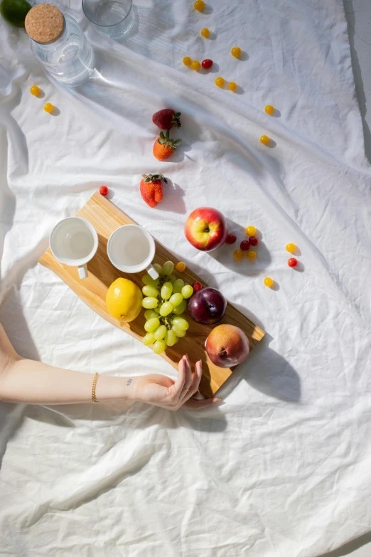 a woman holding a tray of fruit on a bed