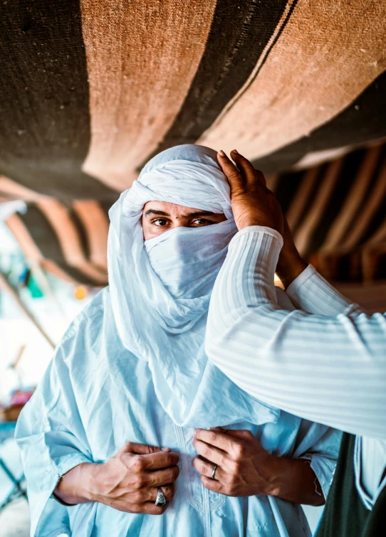 two women standing under a shelter wearing head coverings