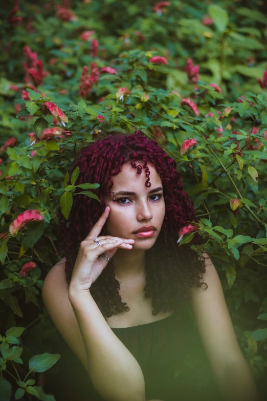 a girl sitting in flowers with her hand on her chin