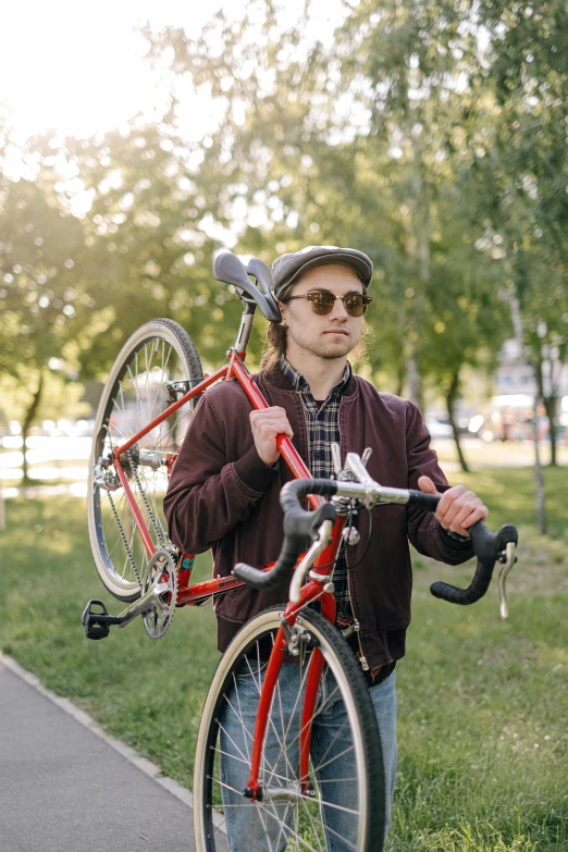 a man wearing a hat is carrying a red bike with two bicycles on it