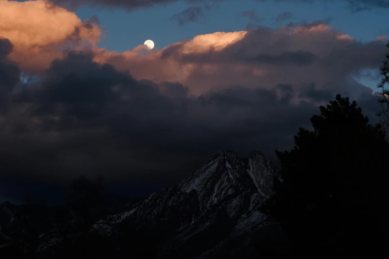 a moon shines brightly through the clouds in a landscape