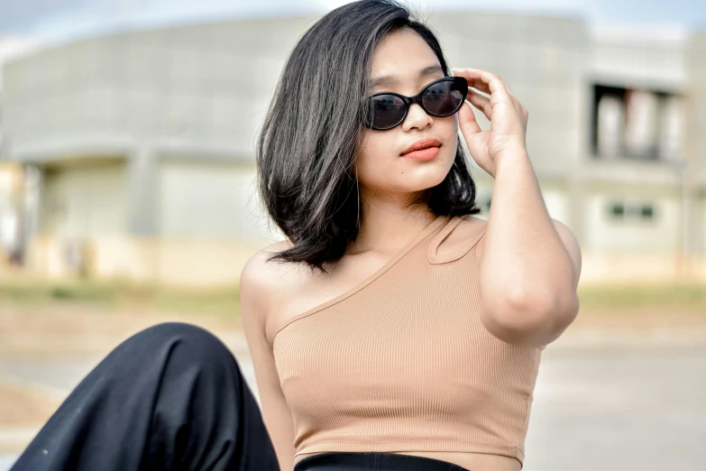 a woman in black pants is wearing a tan top and sunglasses