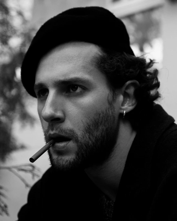 a man with a beard holding a cigarette