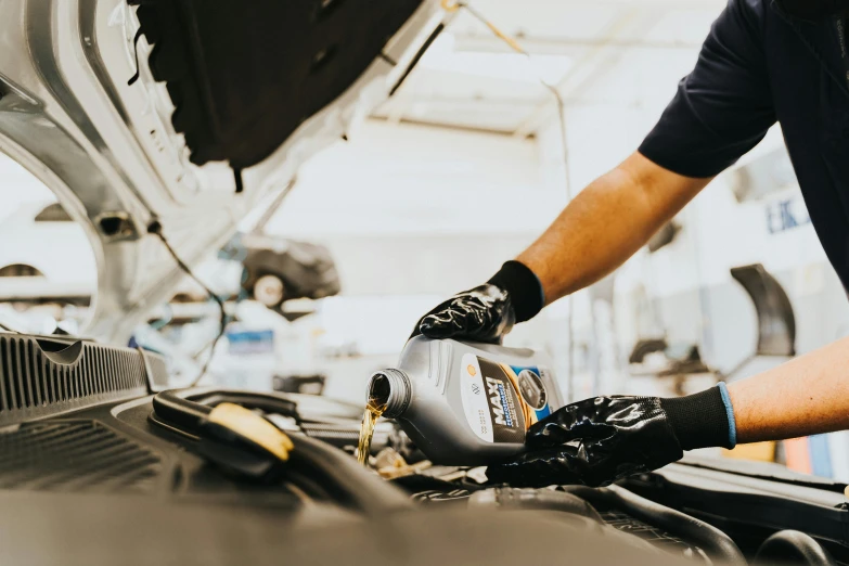 a man pouring the oil onto his car engine