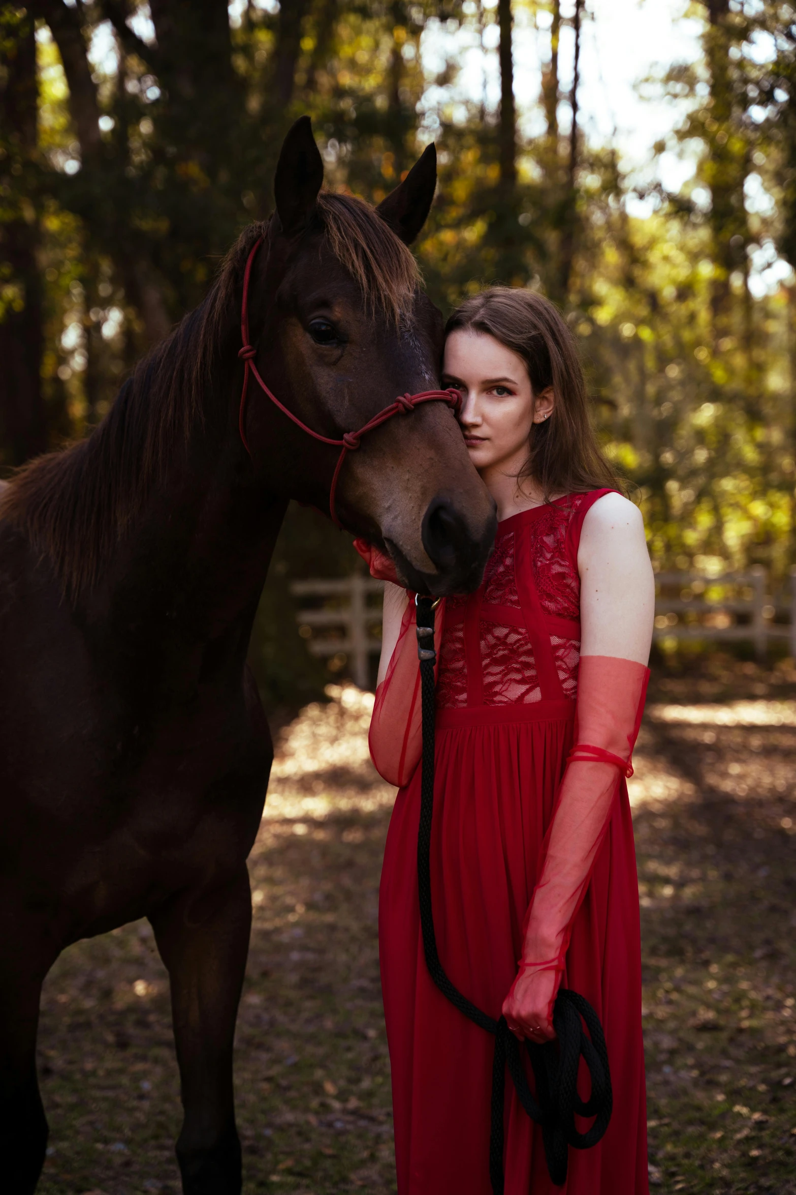 a woman wearing red is standing near a horse