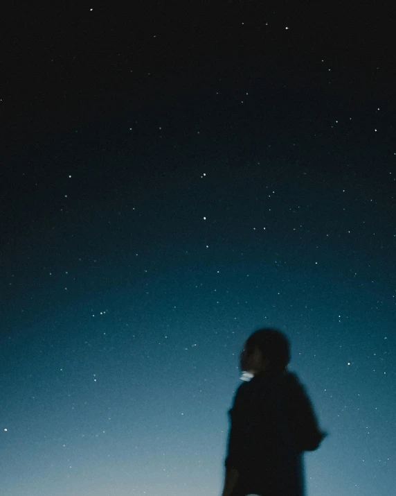 silhouetted person at night under stars on the sky