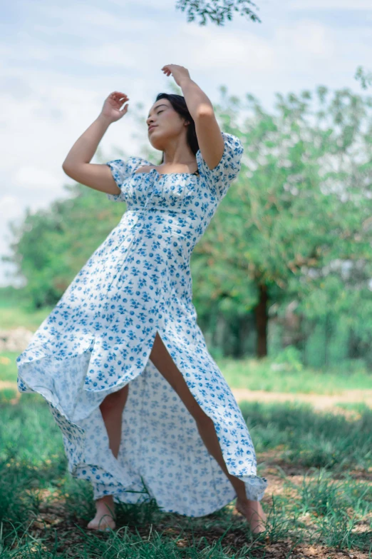 a woman in a dress holds a bunch of green leaves