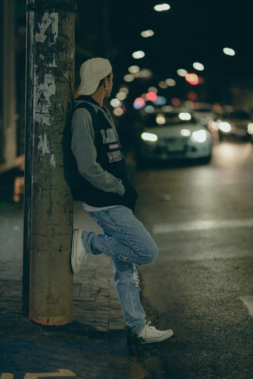 a man is leaning against the pole and waiting for the bus