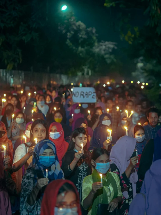 many people are wearing masks while they hold candles and signs