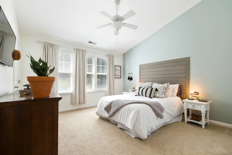 a bed room with a neatly made bed and a tv on the wall