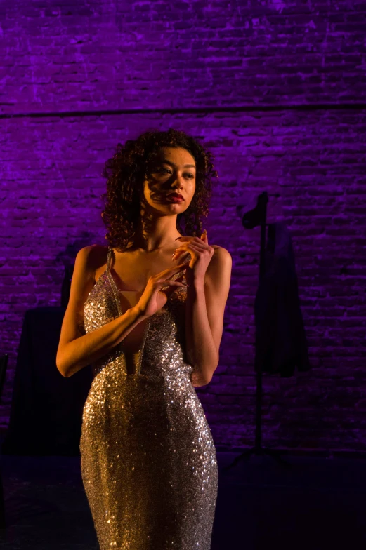 a woman in gold dress standing in front of a purple backdrop