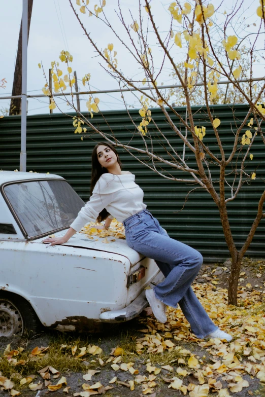 a woman is leaning on the hood of an old car