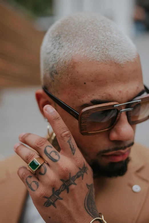 a man with tattoos is wearing sunglasses and holding a cell phone to his ear