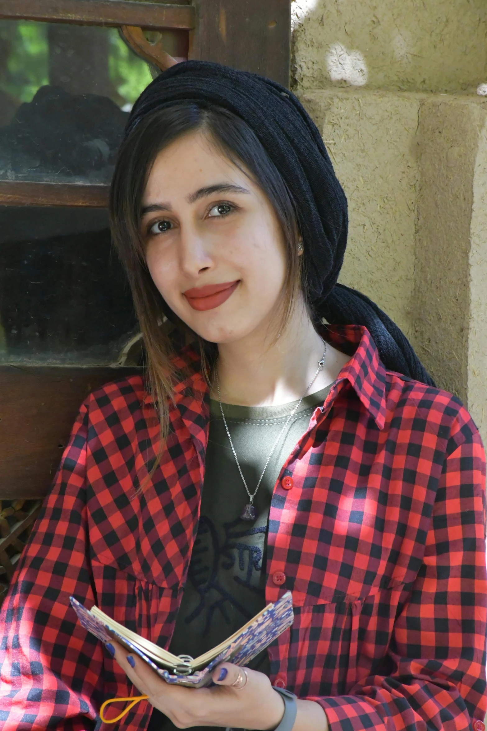 woman wearing plaid jacket smiling while reading a book