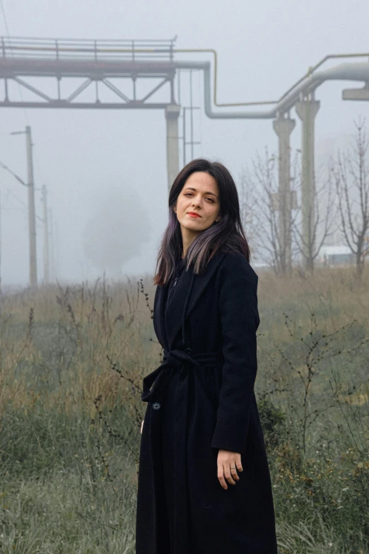 a woman is standing in the fog in the field
