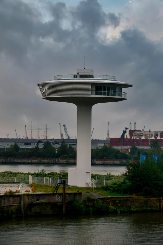 a very tall building near the water under a cloudy sky