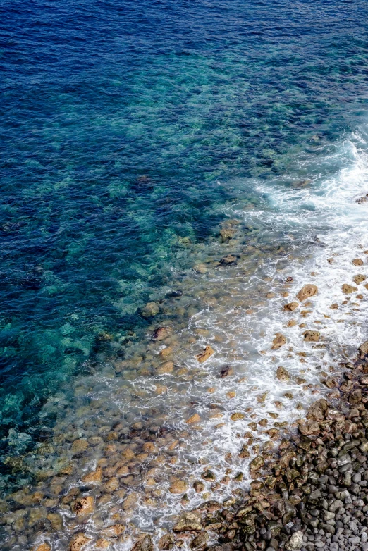 waves and rock beach next to clear blue water