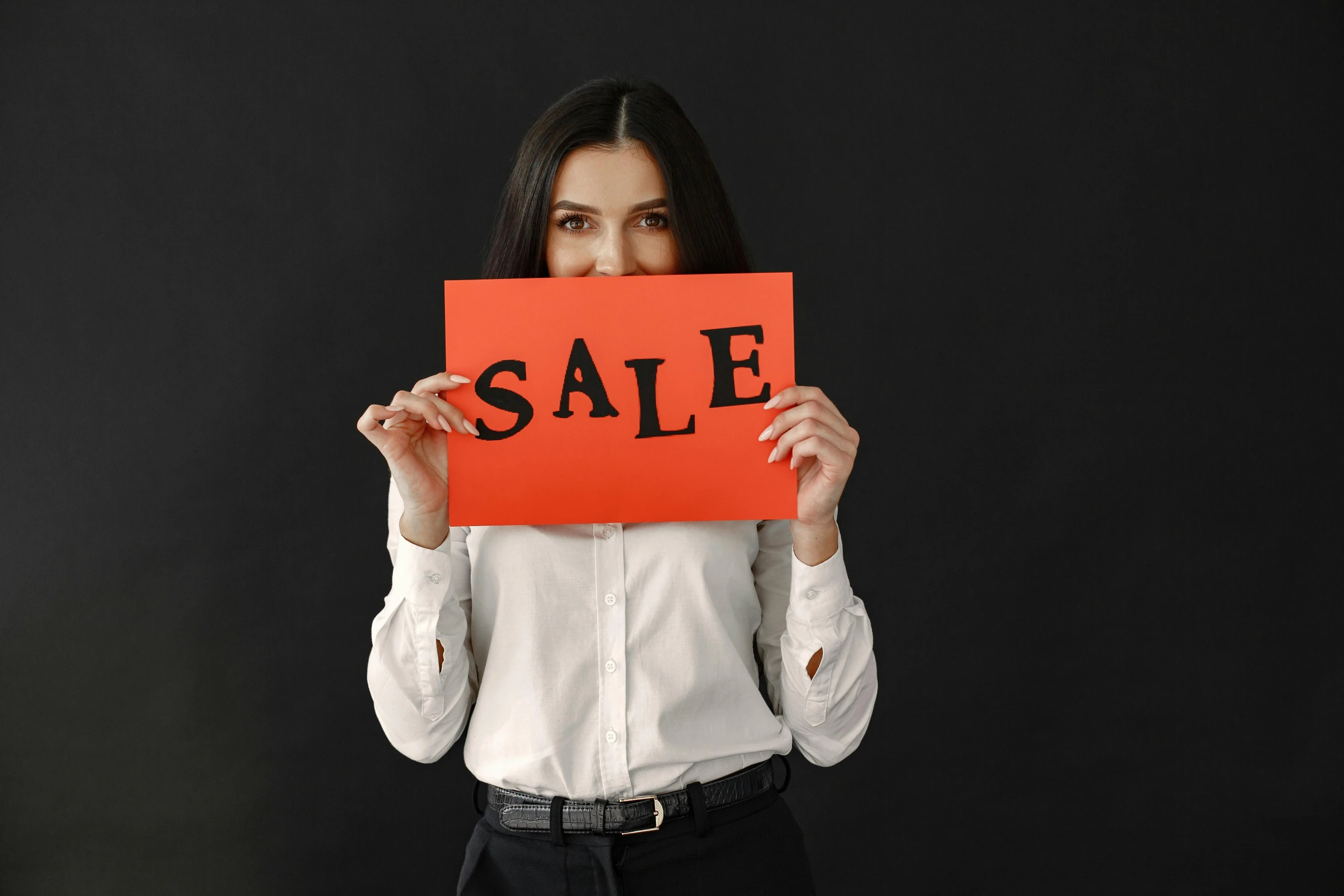 a woman holding a red sale sign in front of her face