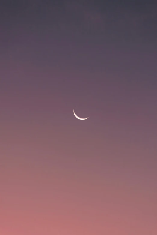 a crescent moon shines brightly in the sunset as the sun sets