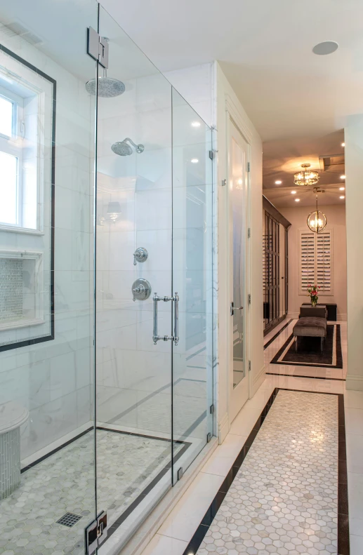 a long bathroom with a glass enclosed shower and black accents