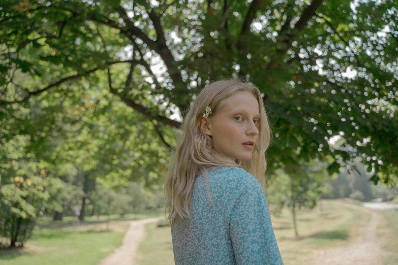 a woman standing in front of a tree near a trail